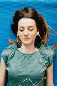 Une jeune fille avec des écouteurs dans les oreilles, profite de la séance de kinésiologie à distance par téléphone ou online